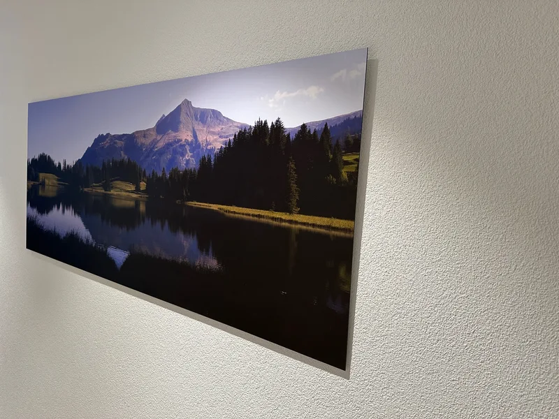Das grossformatige Lauenensee-Panorama hängt an einer hellen Wand; Berge und Wald spiegeln sich im See.