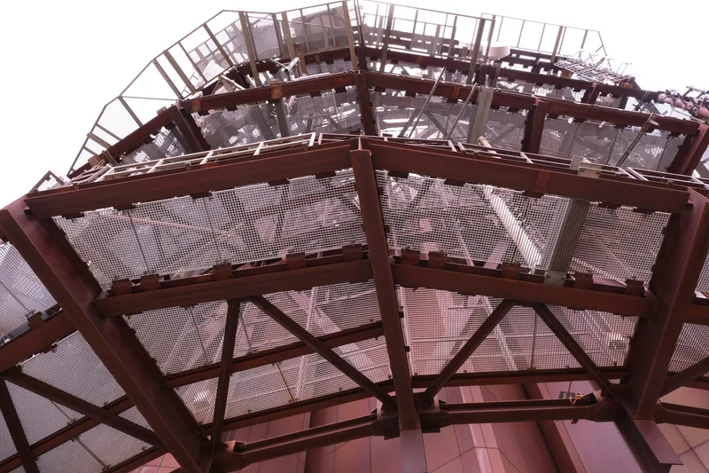 Blick von unten in eine hohe Metallkonstruktion mit Treppen und Plattformen.